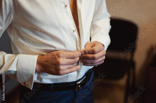 man buttoning his shirt © ViDi Studio