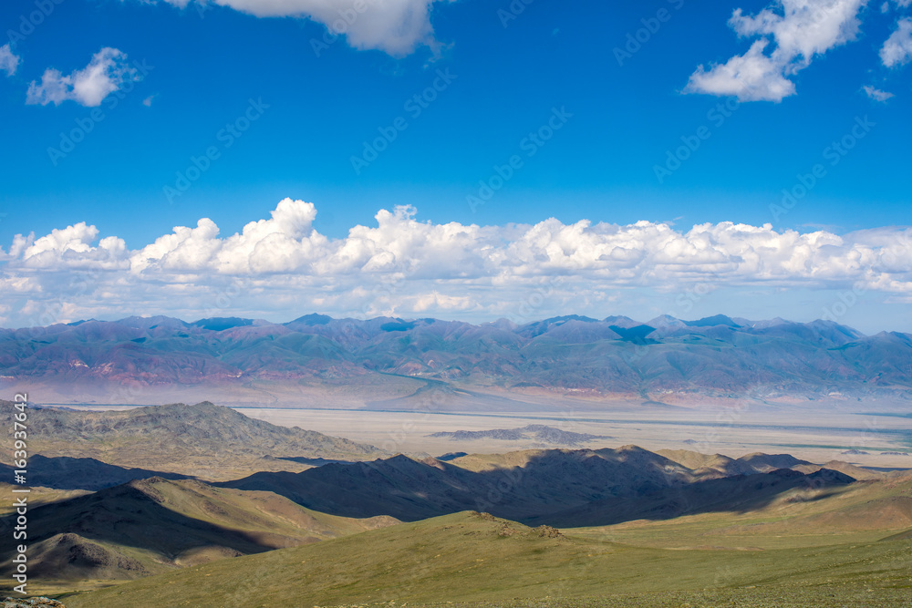 Naklejka premium shadows of fluffy clouds over green hills at sunny day