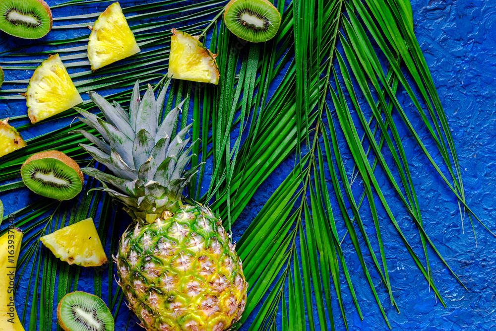 Fototapeta Koncepcja letnich owoców tropikalnych. Kiwi, ananasa i palmy gałąź na błękita stołu tła odgórnym widoku