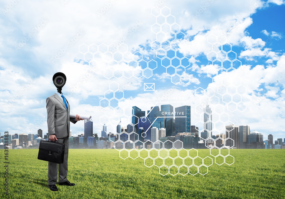 Camera headed man standing on green grass against modern cityscape Camera headed man standing on green grass against modern cityscape