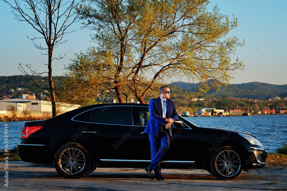 Businessman near the car at sunset Businessman near the car at sunset