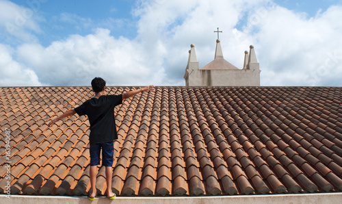 Calabria: un ragazzo di spalle cammina in equilibrio sul tetto della chiesa di Santa Maria dell'Isola a Tropea, una delle destinazioni turistiche più famose del Sud Italia photo