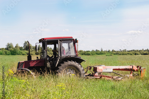 Old small tractor mows the grass