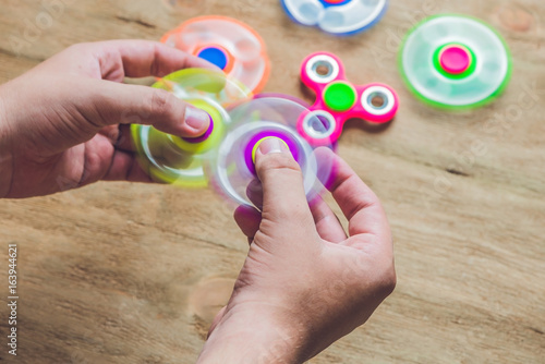 A man hand holding hand spinner or fidget spinner over wooden background
