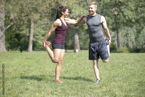 Woman doing stretching exercises with personal trainer in park