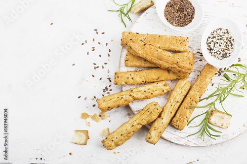 Bread sticks from puff pastry with flax and sesame seeds on a light background with rosemary. Top View.