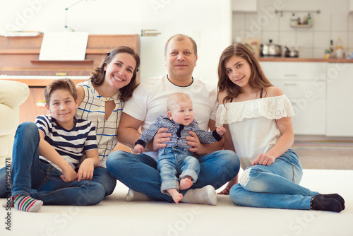 Portrait of young happy family with pretty teenager daughter and son having fun together