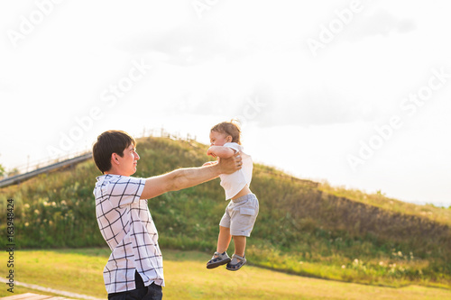 Happy child, dad and son having fun, holding on hands on a sunlight sunset background. Family, travel, vacation, childhood, father's day - concept