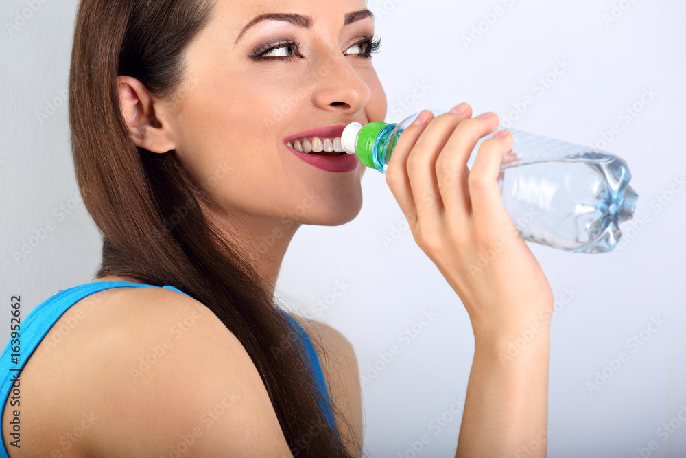 Beautiful happy toothy smiling makeup woman drinking water from the bottle. Healthy face skin. Closeup portrait. Beautiful happy toothy smiling makeup woman drinking water from the bottle. Healthy face skin. Closeup portrait.