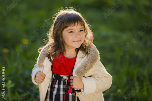 Beautiful girl with long hair in motion whirls and smiles  during sunset in the park. The concept of childhood and freedom.