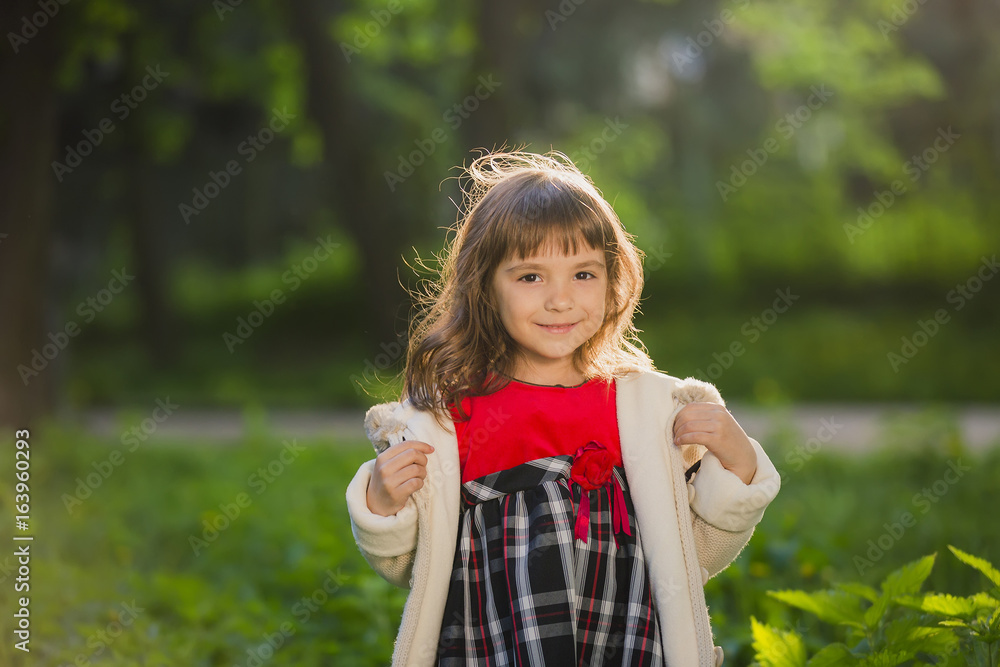 Beautiful girl with long hair in motion whirls and smiles, during sunset in the park. The concept of childhood and freedom. Beautiful girl with long hair in motion whirls and smiles, during sunset in the park. The concept of childhood and freedom.