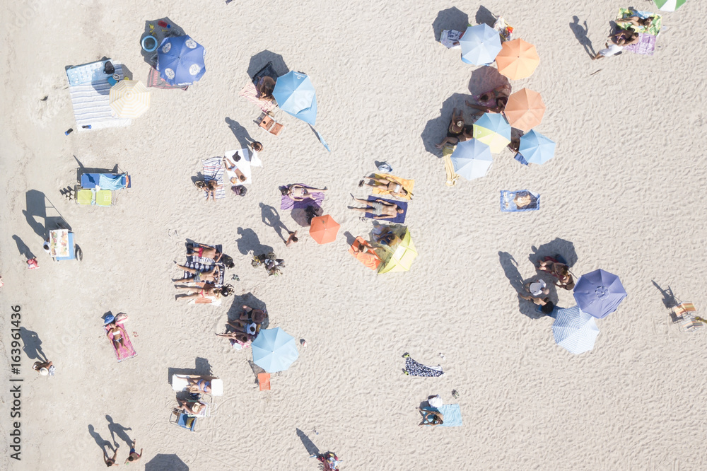 Aerial view of an amazing white beach with colorful beach umbrellas and people sunbathing. Sardinia is the second largest island in the Mediterranean Sea.