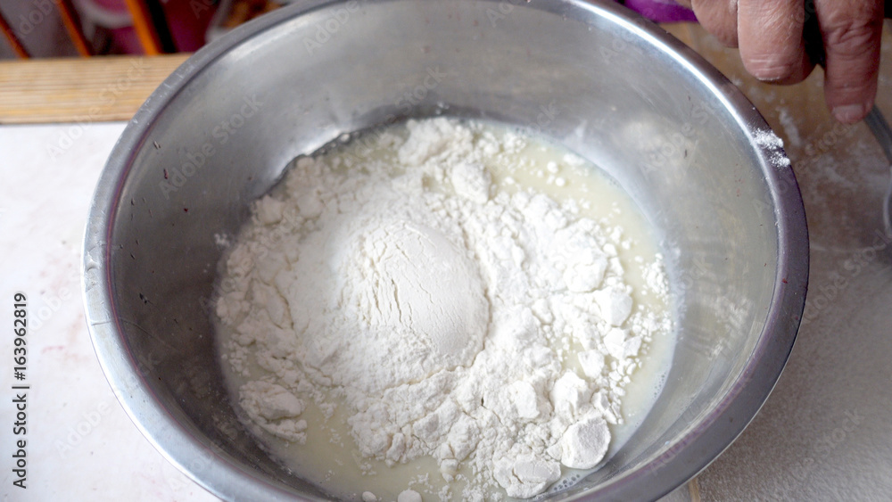 Adding flour to the base for the dough in a metal bowl Adding flour to the base for the dough in a metal bowl