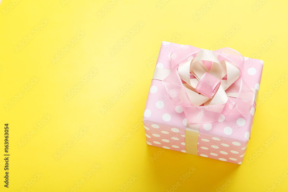 Gift box with ribbon on yellow background Gift box with ribbon on yellow background
