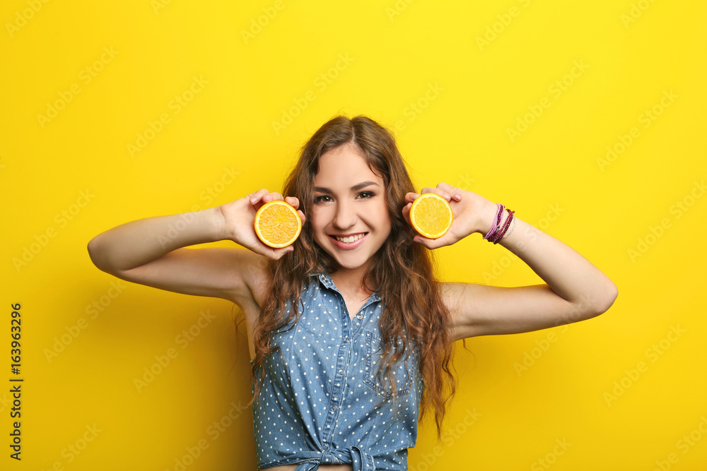 Portrait of young woman with orange fruit on yellow background Portrait of young woman with orange fruit on yellow background