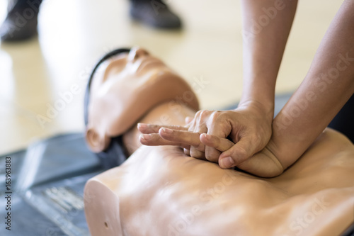 CPR training medical procedure - Demonstrating chest compressions on CPR doll in the class photo