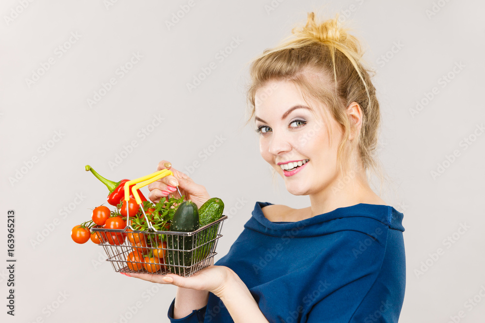 Woman holds shopping basket with vegetables Woman holds shopping basket with vegetables