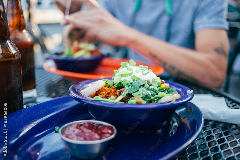 Man on a date in restaurant eats a bowl of fresh vegetables rice and shrimps, served with cold beer bottles, delicious, healthy and tasty dinner