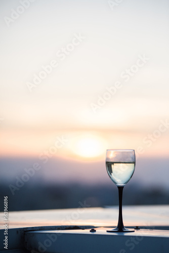 A glass with a white wine in the light of the setting sun. Vibrant alcohol background.