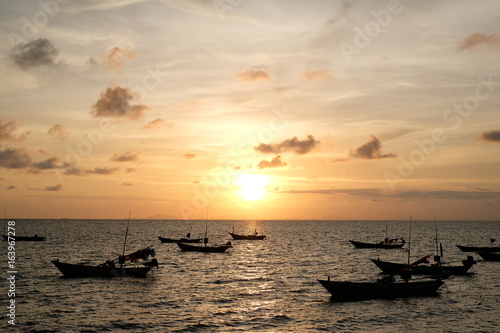 Beautiful sunset and silhouette fisherman boat in the ocean