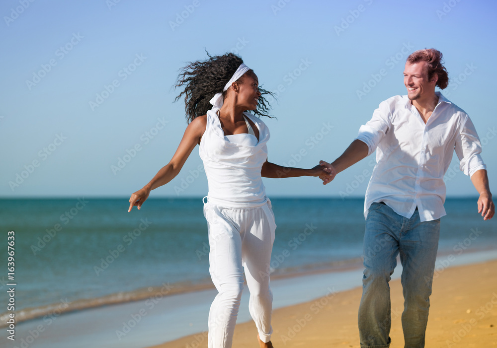 Young couple on a beach in their vacation having fun running Young couple on a beach in their vacation having fun running