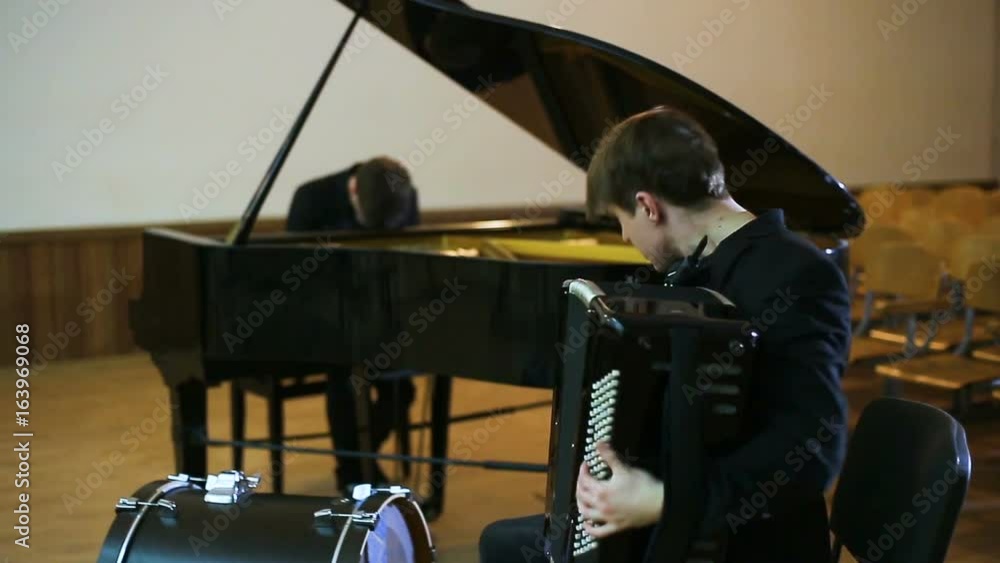 Duet pianist and accordionist playing music in empty room Duet pianist and accordionist playing music in empty room