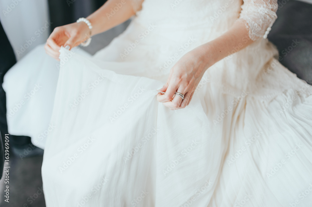Closeup toned photo of beautiful bride tying up her wedding dress Closeup toned photo of beautiful bride tying up her wedding dress