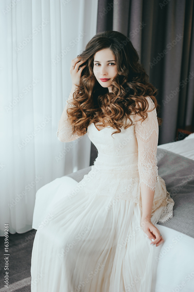 Luxury stylish bride sitting on the bed and looking at the camera