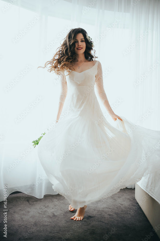 The bride posing against the window. Flying dress