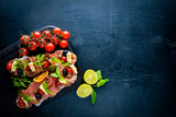 Bruschetta with meat, olives, herbs and parmesan cheese on bread. Cold snacks. Italian cuisine. On Wooden background.