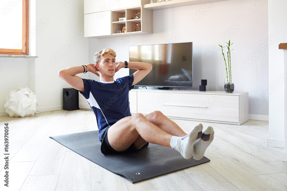 Obraz premium Ragazzo fitness a casa con addominali