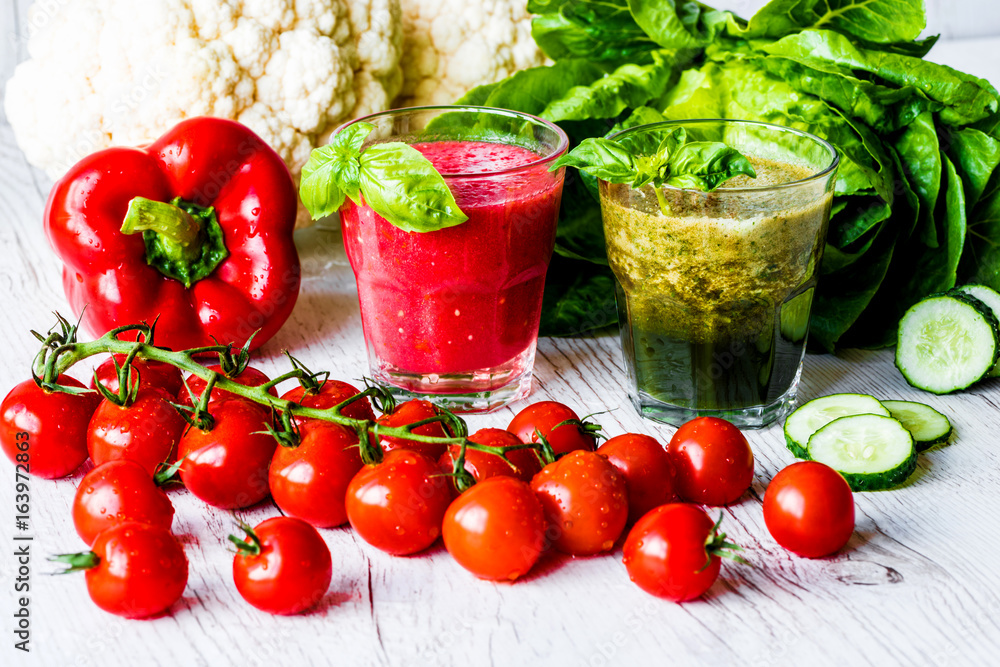 Fresh tomato juice and green detox smoothie in two glasses on a white wooden background Fresh tomato juice and green detox smoothie in two glasses on a white wooden background