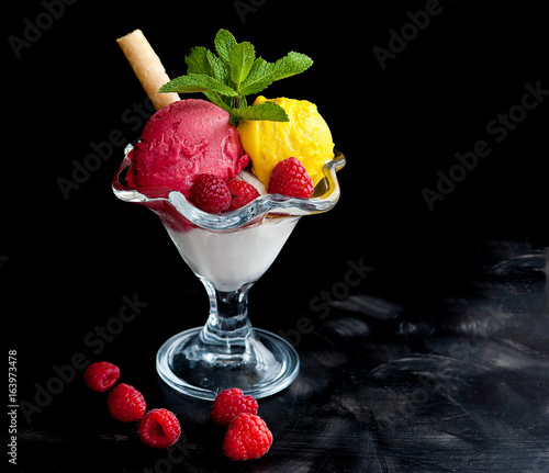 Ice cream in a glass cube with raspberries and mango