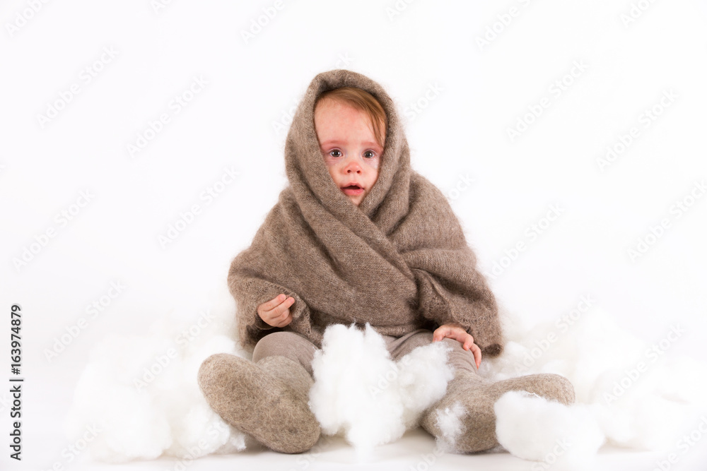 Cute baby girl in a woolen shawl and boots on white background Cute baby girl in a woolen shawl and boots on white background