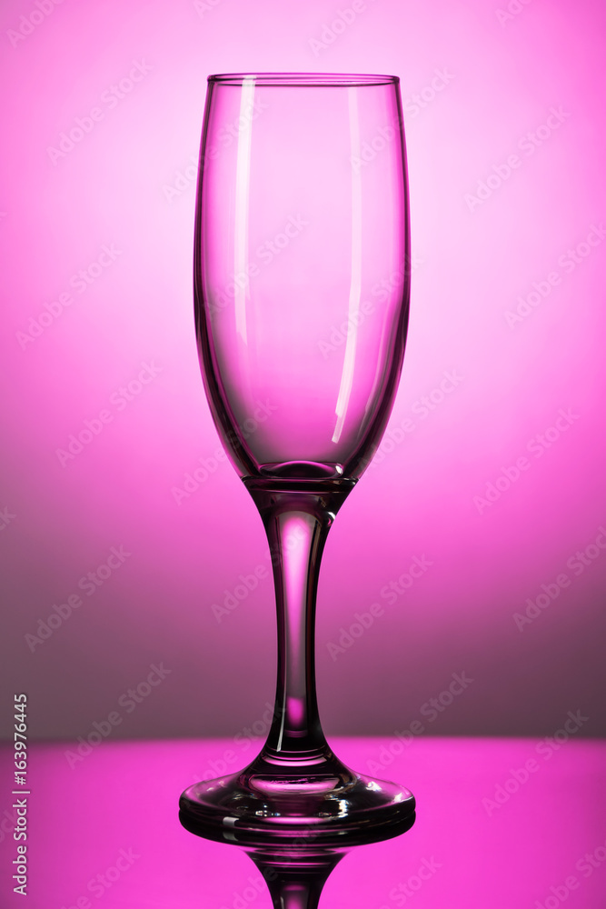 Empty champagne glass on a lumen on a purple background