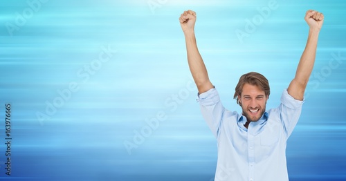 Man celebrating against blurry blue background
