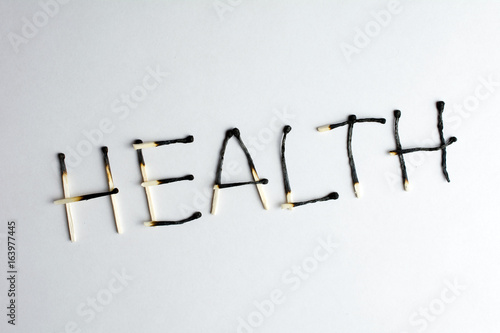 poor health concept health degradation Burnt matches lined with the word health Deterioration of health closeup