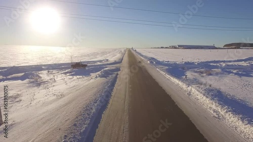 Aerial Roadways. Suv driving in white snowy evergreen forest on slippery asphalt road. Aerial view of the road and the fields in the winter photo