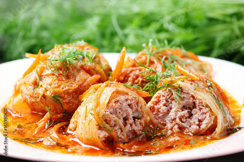 Cabbage rolls in tomato gravy with carrots and fresh dill on a white plate. Сlose-up. photo