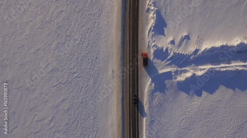 Aerial view of snowy fields and road. SUV driving on winter roads through the snowy field. Aerial view of the car driving on road and the fields in the winter photo