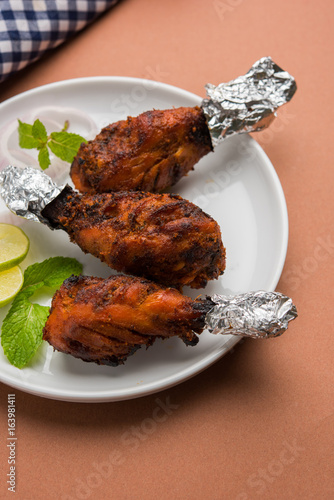 Chicken Tangri kabab or kebab - three Chicken leg pieces marinated with red sauce then grilled and served with salad. It can be served with green chutney photo