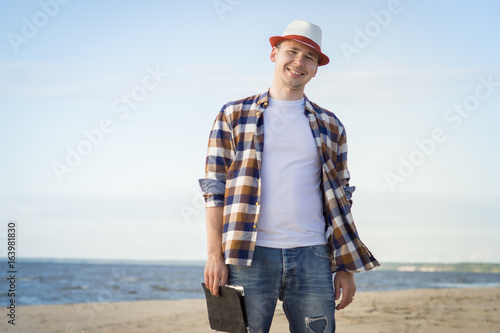 A man in smart casual hipster style with tablet combining work with relax on the beach of Baltic Sea