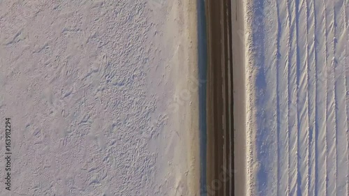Suv rides on road through the snowy field. Aerial view on a snowy field and road from quadrocopter. Aerial view of snowy fields and road photo