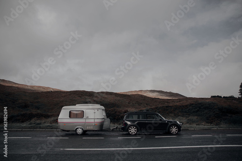Side view of car towing caravan on road