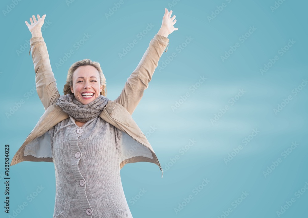 Woman in winter coat celebrating against blurry blue background Woman in winter coat celebrating against blurry blue background