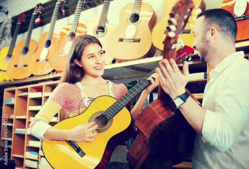 Couple playing guitars in music shop.