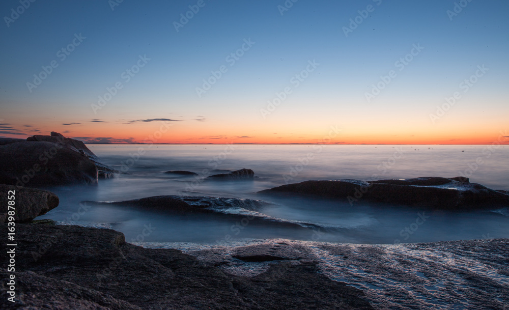 Waves crashing over the rocks as the sun sets over the Atlantic Ocean