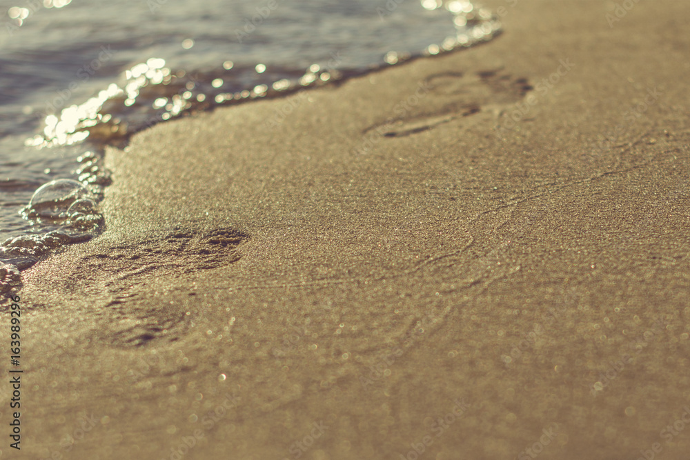 Barefoot footprints on the beach with a wave coming in. Summer vacation. Barefoot footprints on the beach with a wave coming in. Summer vacation.