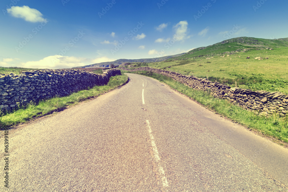 Naklejka premium Stonewall Along Empty Asphalt Road in Lake District UK