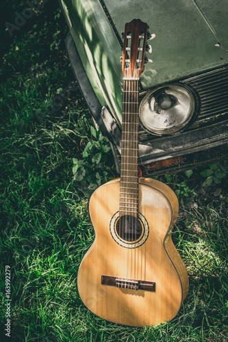 Guitar on a grass next to a vintage car